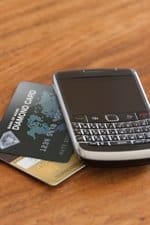 A close up of a blackberry with two credit cards