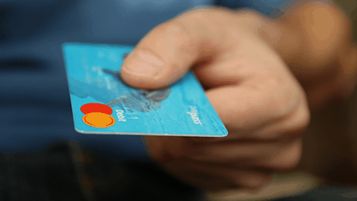 A close up of a someone handing over their teal credit card.