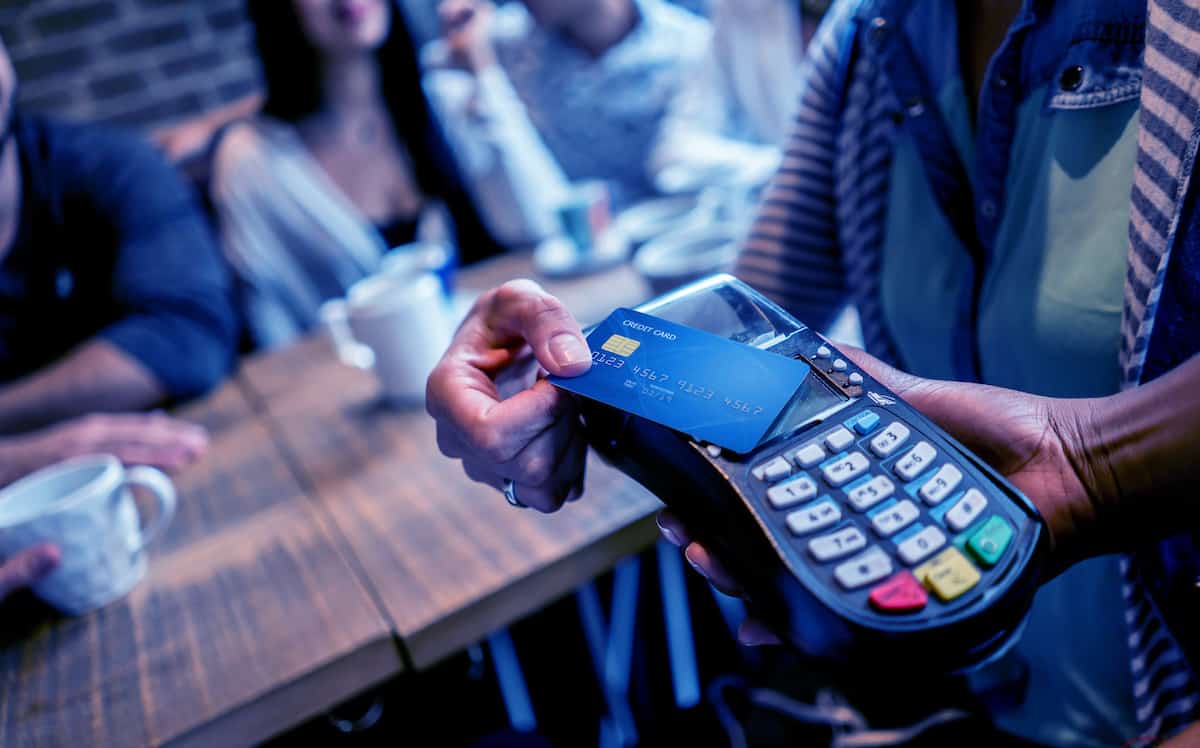 A person paying with a credit card using tap to pay at a restaurant table